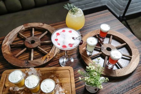 Foto de Una mesa de madera que muestra una variedad de bebidas, incluyendo cócteles, refrescos y jugos. - Imagen libre de derechos