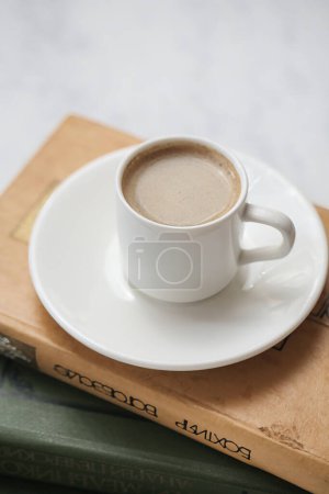 Téléchargez les photos : Une tasse de café repose sur une pile de livres. - en image libre de droit