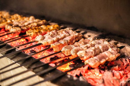 A BBQ grill is cooking a variety of meat and vegetables, creating a delicious and savory meal.