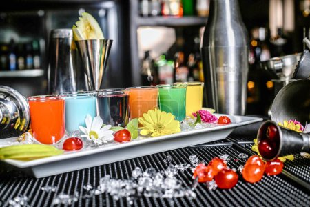 A vibrant assortment of drinks decoratively arranged on a bar counter in a tray with various glasses and garnishes.