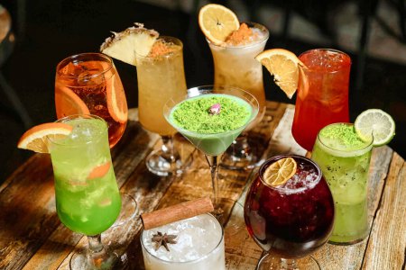 Foto de Una mesa de madera cubierta de una variedad de diferentes tipos de bebidas, incluyendo cócteles, jugos y bebidas, perfectamente organizados. - Imagen libre de derechos