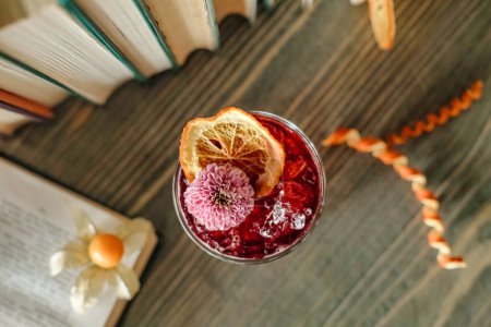 Photo for A glass filled with a refreshing drink is placed next to an open book on a wooden table. - Royalty Free Image