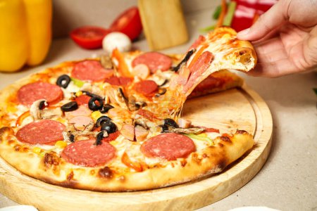 A persons hand reaching towards a delicious slice of pepperoni pizza on a plate.