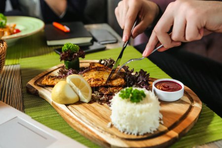 Photo for A person is cutting food on a wooden cutting board, using a chefs knife. - Royalty Free Image