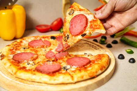 Une personne attrape joyeusement une tranche de pizza pepperoni piquante d'une table remplie lors d'une fête animée.