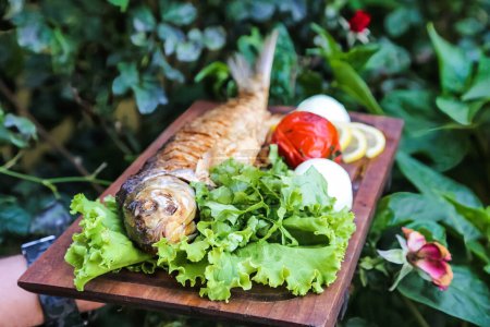 Ein Holzschneidebrett mit frischem Salat und Fisch.