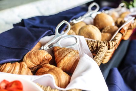 A basket filled with a variety of food items, prominently featuring croissants.