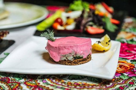 Ein Teller mit rosa Dessert steht neben anderen Tellern, die mit verschiedenen Lebensmitteln gefüllt sind..