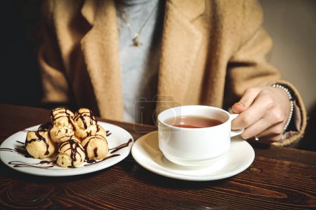 Eine Person sitzt an einem Tisch und genießt eine Mahlzeit, die aus einem Teller mit Essen und einer Tasse Tee besteht..