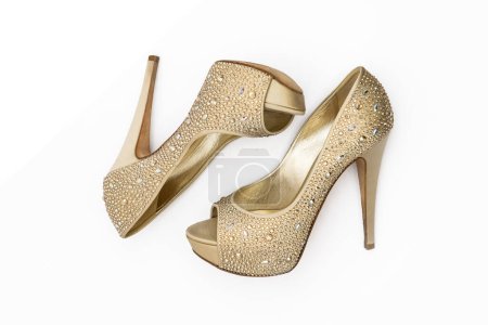 Téléchargez les photos : Chaussures dorées brillantes avec des pierres à talons hauts sur fond blanc - en image libre de droit