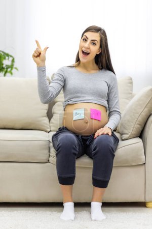 Photo for Photo of pregnant woman with blue and pink papers on her stomach showing thumb ups. Concept of pregnant woman. - Royalty Free Image