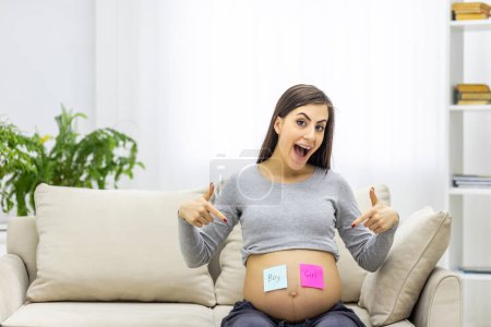 Photo for Photo of positive pregnant woman with pink and blue papers on the stomach which mean gender of future baby. Concept of pregnant woman. - Royalty Free Image