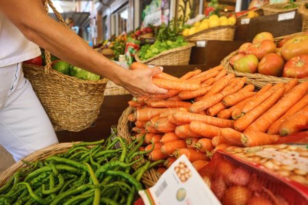 Foto de Compra de productos orgánicos frescos en el mercado de los agricultores. Una mujer elige hierbas frescas, verduras y frutas en una feria de alimentos. Foto de alta calidad - Imagen libre de derechos
