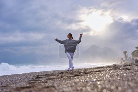Téléchargez les photos : Jeune femme sur la plage de sable et regarder les vagues de la mer - en image libre de droit