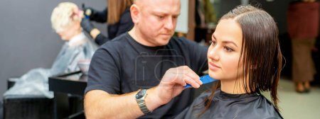 Photo pour Coupe de cheveux de longs cheveux mouillés de jeune femme caucasienne par un coiffeur masculin dans un salon de coiffure - image libre de droit