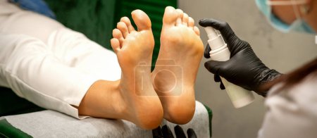 Téléchargez les photos : Une femme obtenant une pédicure et pédicure hydratant pieds féminins avec de la lotion pulvérisation dans un salon de beauté - en image libre de droit
