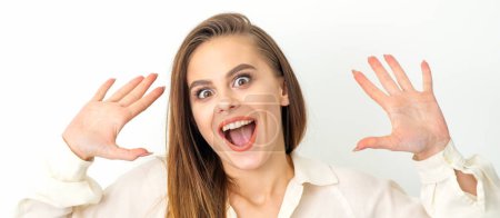 Foto de Retrato de una joven mujer caucásica con camisa blanca levanta las manos y ríe positivamente con la boca abierta posa sobre un fondo blanco - Imagen libre de derechos