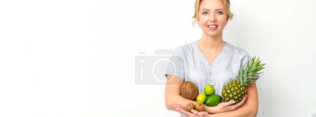 Téléchargez les photos : Portrait d'une jeune femme caucasienne souriante nutritionniste avec différents fruits dans ses mains sur fond blanc - en image libre de droit