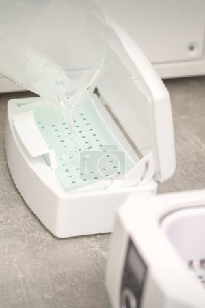 Téléchargez les photos : Ajouter du liquide pour la désinfection des instruments à la machine pour la stérilisation des outils - en image libre de droit