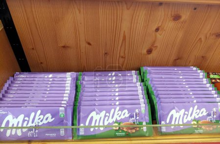 Téléchargez les photos : Une gamme de tablettes de chocolat Milka soigneusement organisées sur les étagères d'un supermarché, mettant en valeur la marque de confiserie populaire. - en image libre de droit