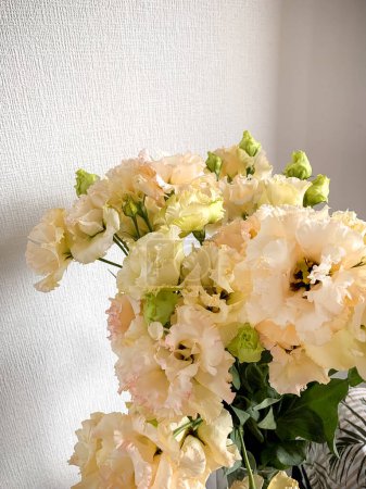 Téléchargez les photos : Photo d'un délicat bouquet de fleurs blanches d'Eustoma en vase sur fond blanc - en image libre de droit