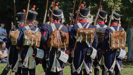Photo for Prague, Czech Republic,  August 12, 2023, Napoleon Day in Prague at Vysehrad. Two rows of men in period red and blue French uniforms, leather and fur sacks on their backs with infantry rifles in their hands - Royalty Free Image