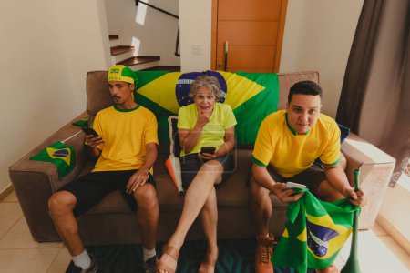 Photo for Group of Soccer Fans Celebrating the cup in the living room watching football game. Multi Ethnics Family Cheering for Brazil to be Champion. - Royalty Free Image