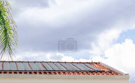Foto de Water Heating System on the Roof of the House in a Sunny and Cloudy Day. Renewable Concept Image. - Imagen libre de derechos