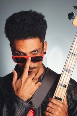 Handsome Black Musician Man With Leather Jacket Holding Bass. Portrait of a Man Wish Red Glasses Holding a Instrument Isolated.