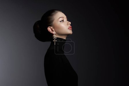 Profile of a graceful woman in a black turtleneck, adorned with ornate cross earrings, exuding elegance and sophistication