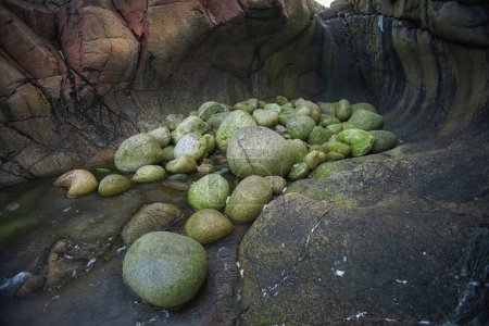 Dragon eggs rocks bask in sunlight within a tranquil rock pool, showcasing natures textures. Teriberka, Russia