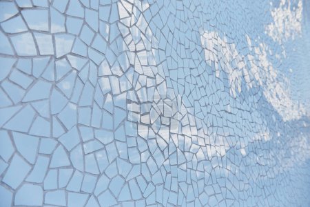 Detaillierte blaue Mosaikfliesenwand mit Sonnenlicht, das seine Oberfläche reflektiert