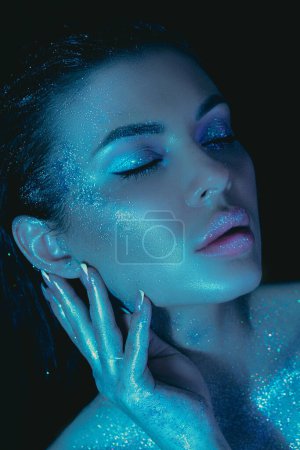 Beauty woman cosmetic makeup, glitter adorning her skin, under dim blue lighting