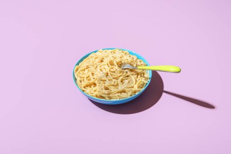 Photo for Classic italian dish, spaghetti with parmesan cheese and black pepper, minimalist on a purple table. Pasta cacio e pepe in bright light on a vibrant colored background - Royalty Free Image
