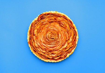 Téléchargez les photos : Vue ci-dessus avec une tarte aux pommes fraîchement cuite, minimaliste sur une table bleue. Pose plate avec une tarte aux pommes maison - en image libre de droit