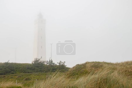Lighthouse in the sand dunes on the beach of Blavand in fog, Jutland Denmark Europe.