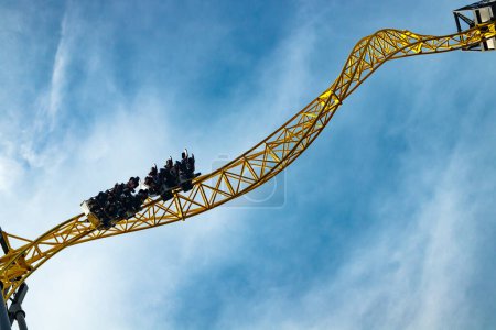 Ride roller coaster in motion in amusement park on blue sky background.
