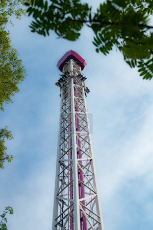 Ride tower in motion in amusement park on blue sky background.