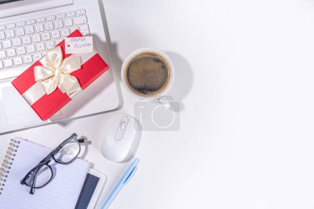 Photo for Present from secret santa on workplace table. Office Christmas and New Year celebration game. Office table surface, notebook with festive gift box, white background flatlay copy space - Royalty Free Image