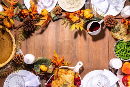 Téléchargez les photos : Thanksgiving table de fête familiale avec assiettes, couverts, verres, plats traditionnels dinde ou poulet cuit au four, tarte à la citrouille, fruits, purée de pommes de terre, haricots verts, fond en bois - en image libre de droit