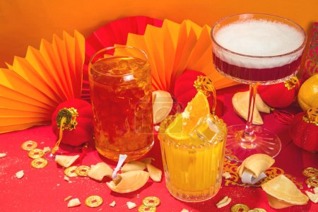 Photo for Chinese New Year Cocktail drinks, set of three different glass with various red gold color alcohol party beverage, with traditional Chinese New Year decor, greeting envelopes, Chinese lanterns, coins - Royalty Free Image