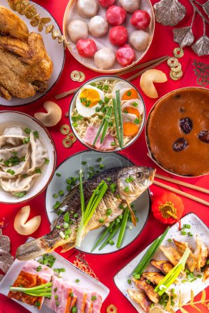 Traditioneller chinesischer Neujahrstisch, Party-Einladung, Menühintergrund mit Schweinefleisch, gebratenem Fisch, Huhn, Reisbällchen, Knödeln, Glückskeksen, nischem Gao-Kuchen, Nudeln, chinesischen Dekorationen