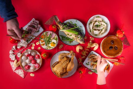 Traditional Chinese lunar New Year dinner table, party invitation, menu background with pork, fried fish, chicken, rice balls, dumplings, fortune cookie, nian gao cake, noodles, chinese decorations