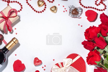 Foto de Valentine's Day greeting card flat lay. Valentine day isolated white background with wine bottle, heart sweets chocolates, bouquet of red roses, gift box, heart shaped candies, confetti, beads - Imagen libre de derechos