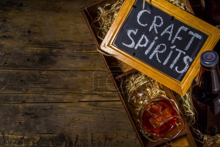 Craft spirit alcohol. Various bottles and glass with hand crafted hard strong alcohol drinks. Old wooden rustic background copy space