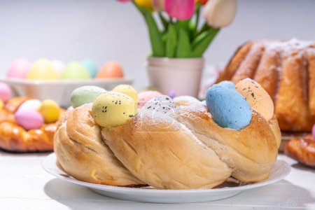 Osterkranzbrot, traditionelles Osterferienbacken, süße Semmelkuchen mit bunten Ostereiern, am Brunch festlich dekorierter Tisch Kopierraum