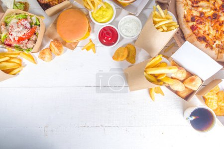 Foto de Entrega fastfood ordenar comida concepto en línea. Gran conjunto de surtido de comida para llevar pizza, papas fritas, nuggets de pollo frito, hamburguesas, ensaladas, alas de pollo, varios lados, fondo de mesa blanco - Imagen libre de derechos
