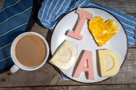 Photo for Father day breakfast sandwiches and scrambled eggs.Homemade father day bacon cheese toasts sandwiches with lettering I love dad, with coffee latte cup, gift box and necktie top view copy space - Royalty Free Image