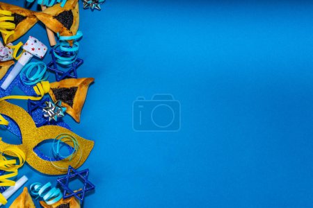 Téléchargez les photos : Jewish holiday Purim greeting card background, jewish spring start holiday carnival flat lay with traditional carnival masks, rattle, gifts and hamantaschen cookie on colorful background - en image libre de droit