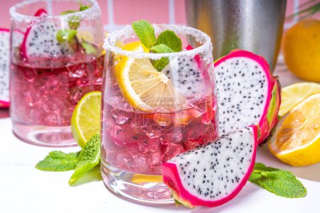 Sweet colorful tropical cocktail with pitaya or dragon fruit, lime and mint. Salted margarita alcohol pitahaya fruit drink over light tile background copy space 